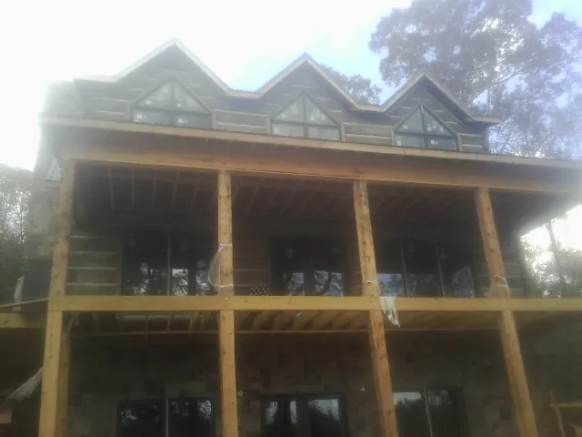 Dormers and porch framing on a large log home under construction — Roof Coating work by our crew in Lynchburg