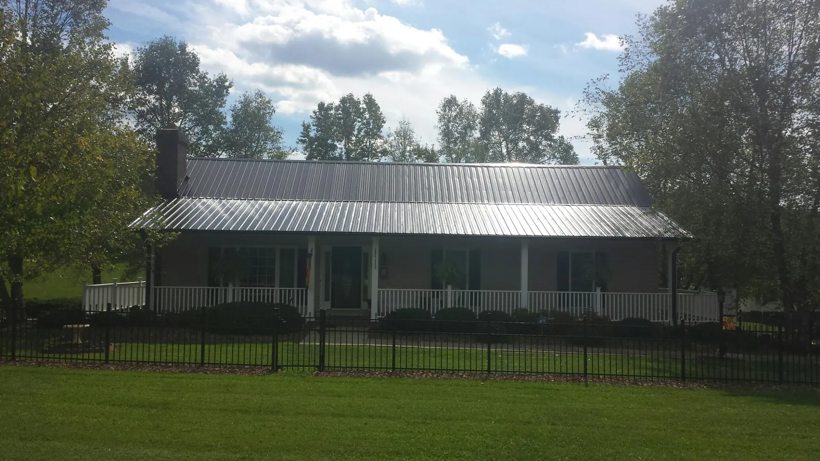 Gray metal roof on a brick ranch with a full width front porch — Gutter Guard Installation work by our crew in Lynchburg